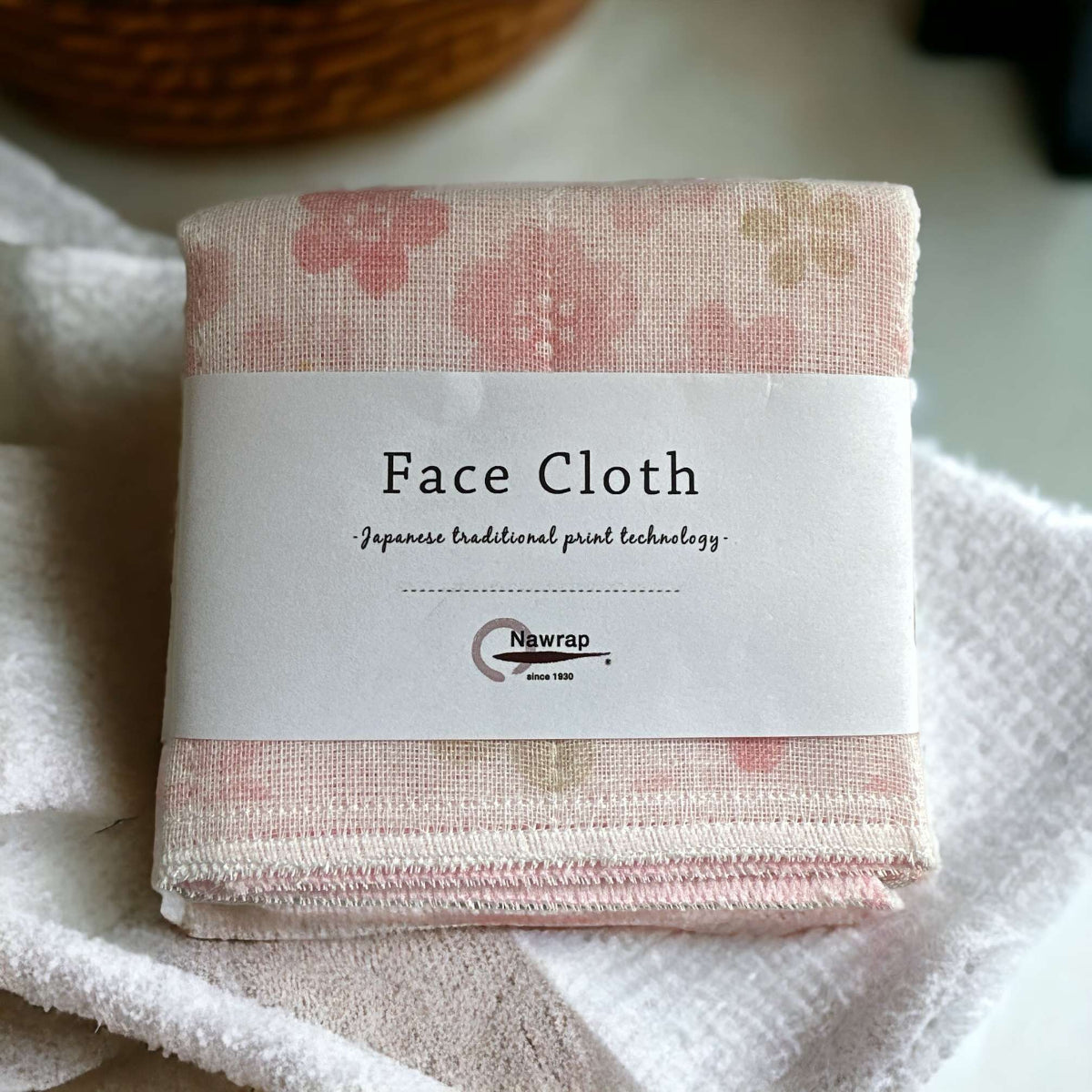 Folded face cloth with floral pattern and Newrap label on a white background