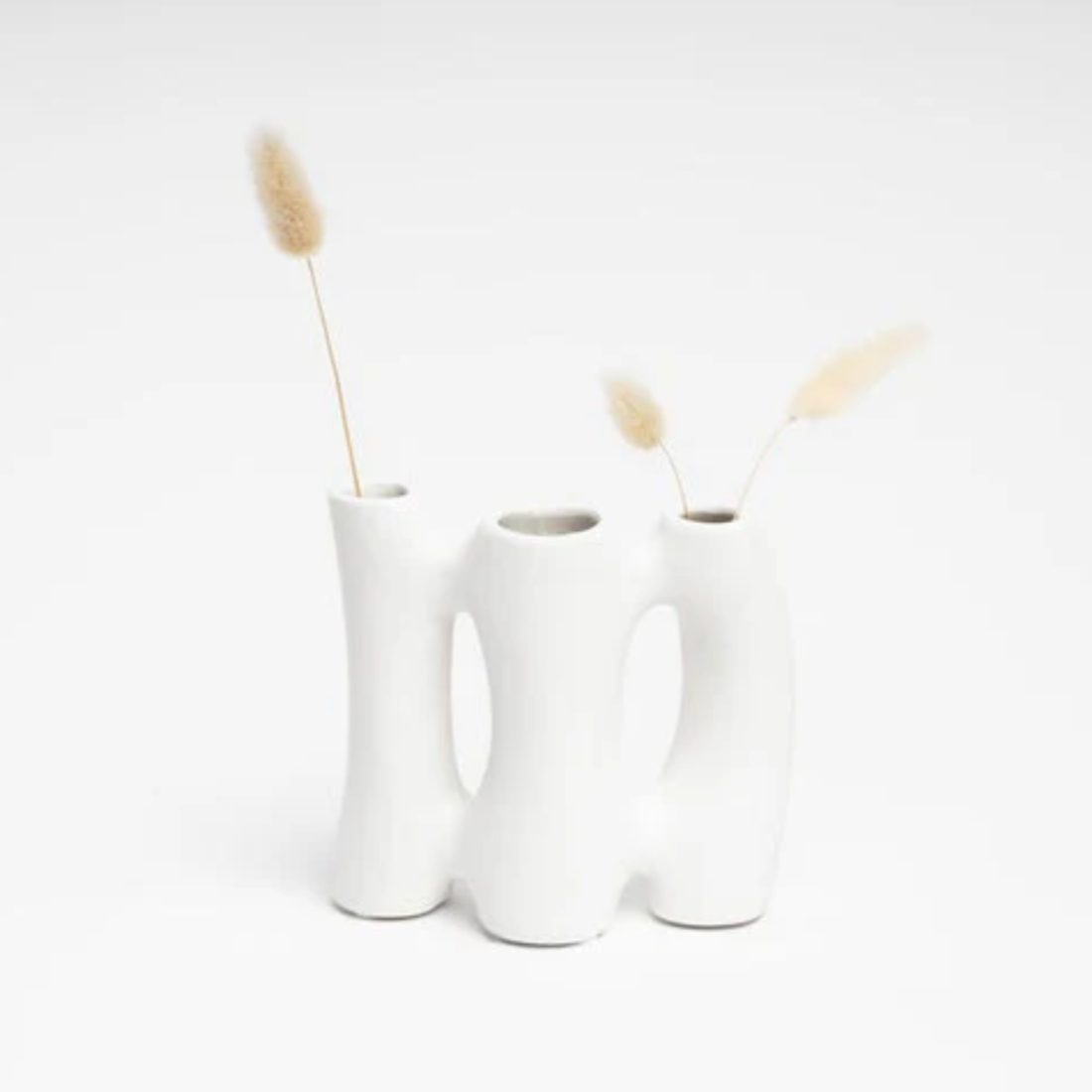 A trio white vase with dried plants on a light gray background