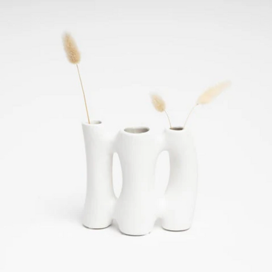A trio white vase with dried plants on a light gray background