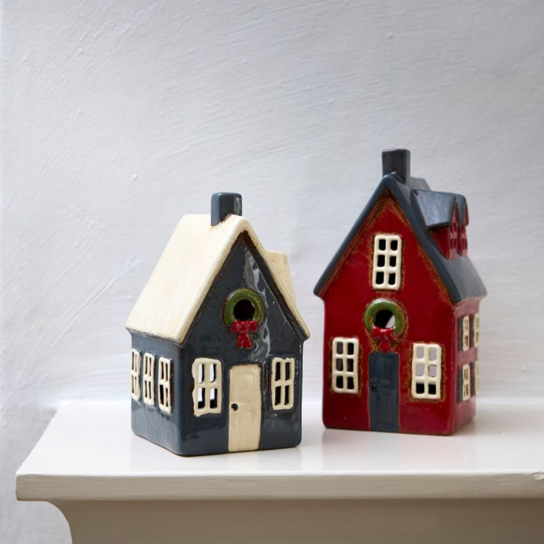 Two ceramic houses, one navy, one red, on a white surface with a light gray background.