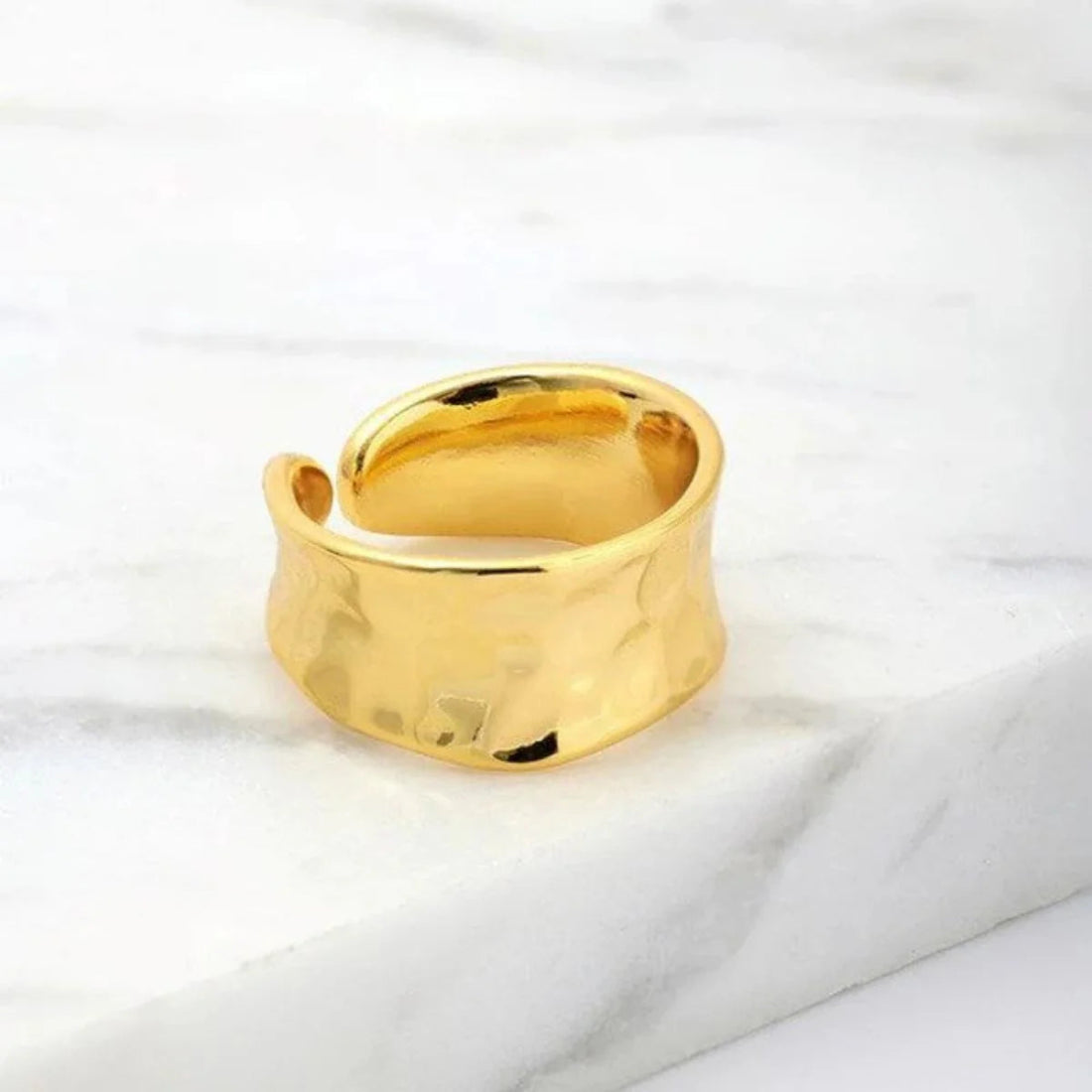 Gold hammered ring on a white marble surface