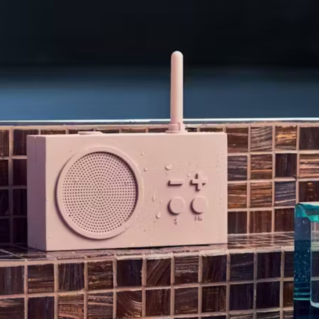 Pink portable radio on a tiled surface with a dark background