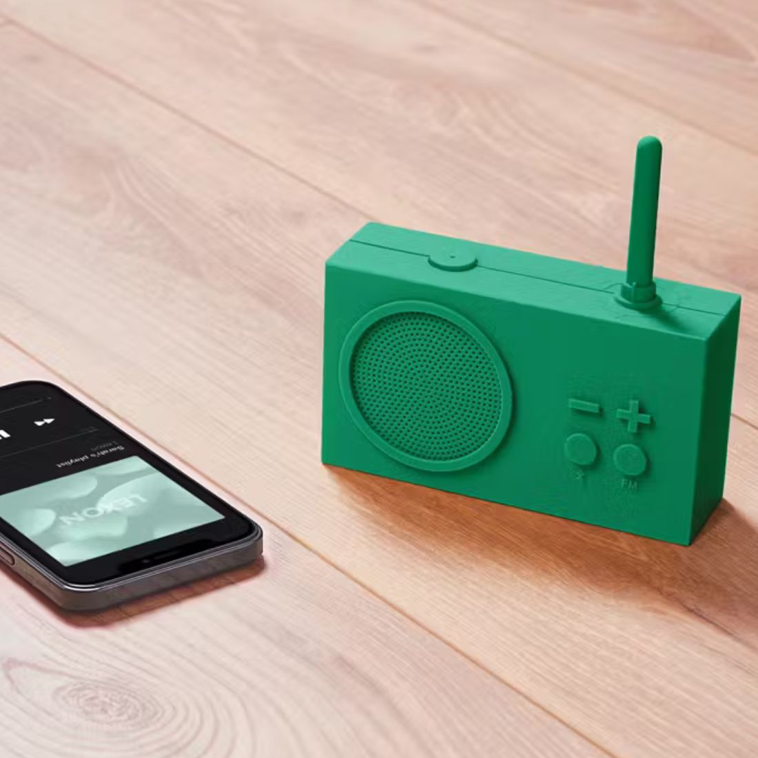 Green radio with smartphone on a wooden surface
