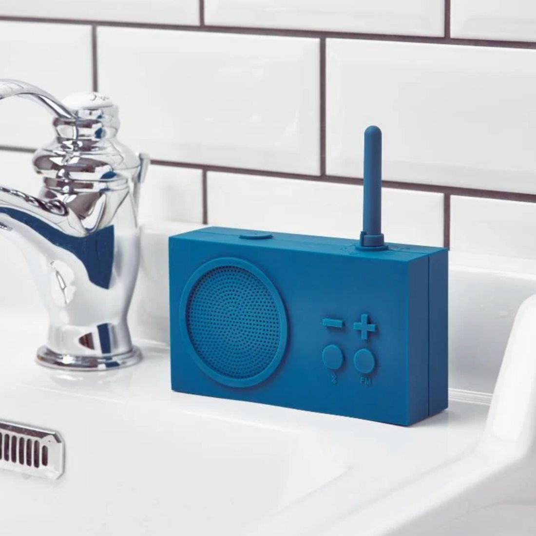 Teal blue portable radio on a white surface with a tiled wall background