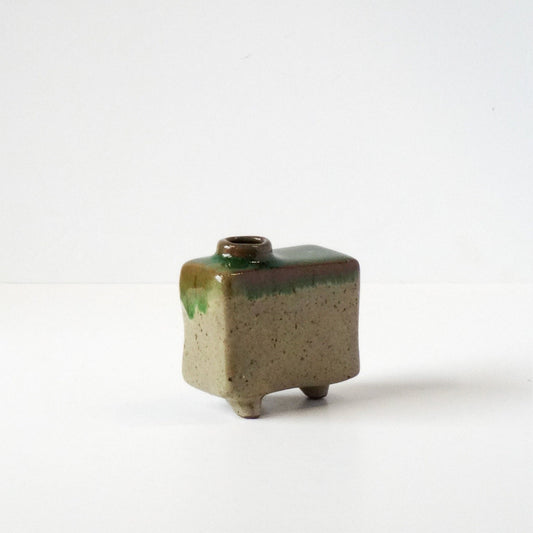 Small square ceramic vase with green and brown glaze on a white background