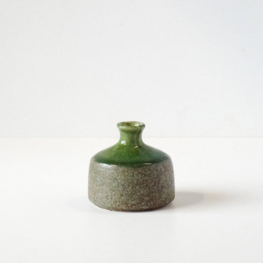 Small ceramic vase with green top and grayish-brown base on a white background