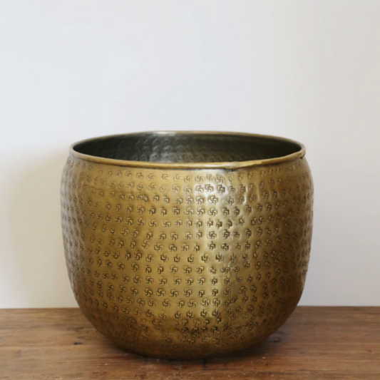 Antique brass textured planter on a wooden surface with a white background