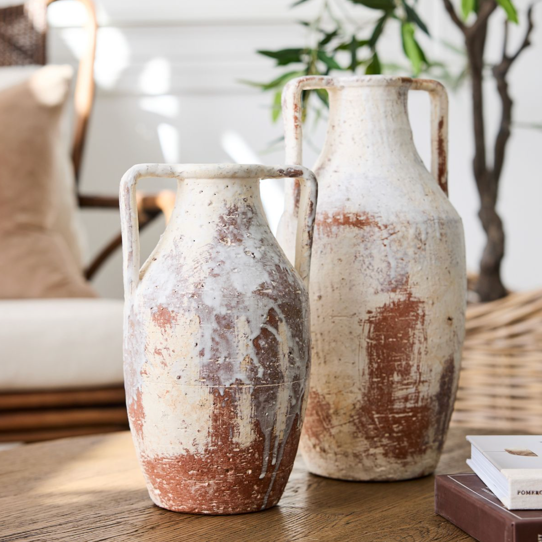 Two rustic ceramic vases on a wooden surface with a blurred indoor background