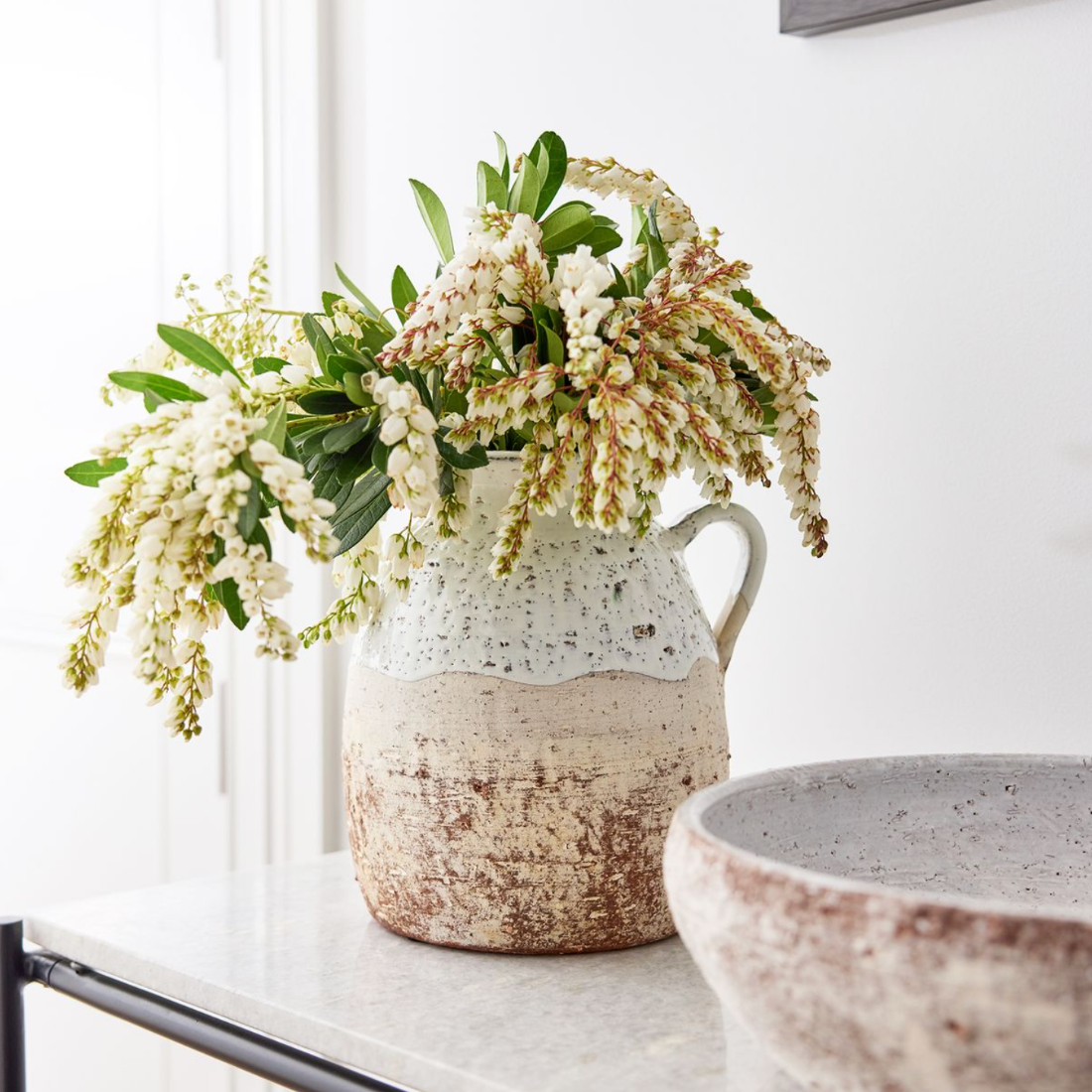 Decorative ceramic vase with flowers on a table against a white wall
