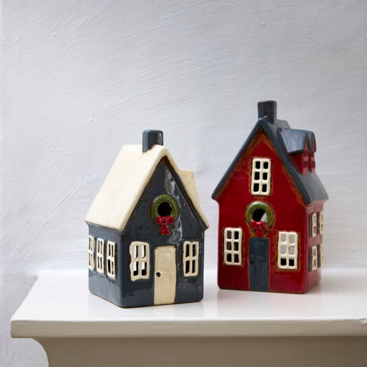Two ceramic houses, one navy, one red, on a white surface with a light gray background.