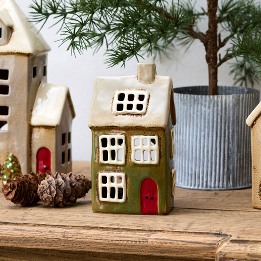 Decorative ceramic house on a wooden surface with a potted plant in the background