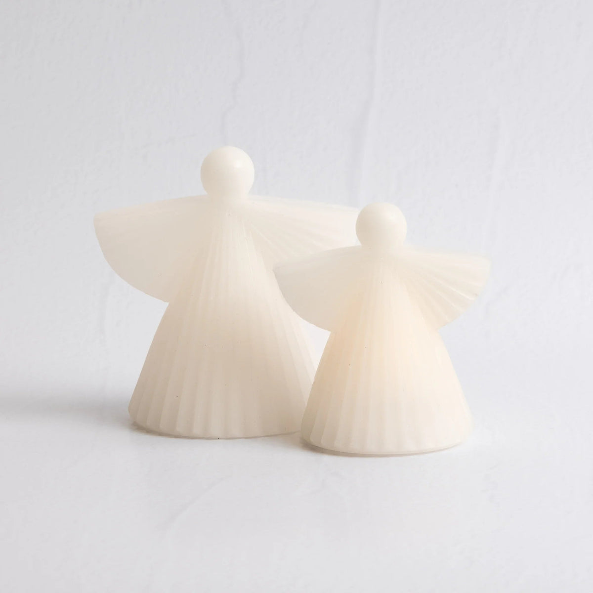 Two white wax LED angel candles on a light background