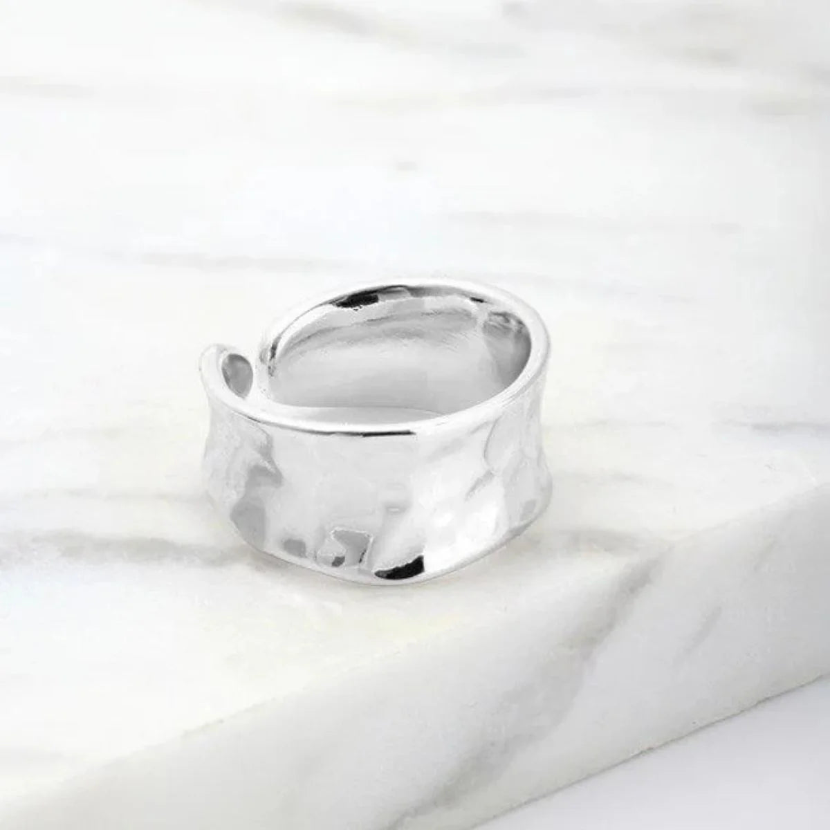 Silver hammered ring on a white fabric background